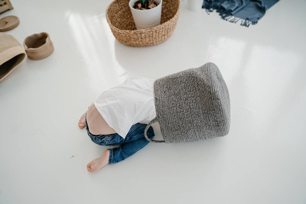 Uma criança de jeans azuis no chão rasteja no saco como um gato
 - Foto, Imagem