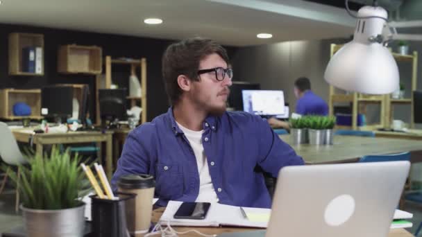 Portret van jonge succesvolle zakenman zittend in modern kantoor en kijkend naar de camera - Video