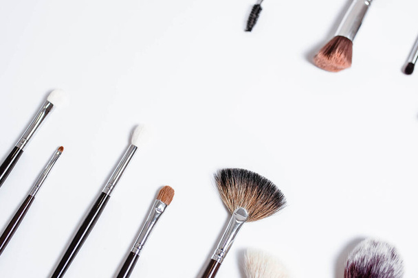 Flat top view a set of professional makeup brushes on a light background. Copy space for your text. Make-up brushe over white background. Aerial view of various brushes. Various makeup brush sizes. - Photo, Image