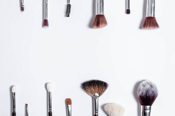 Flat top view a set of professional makeup brushes on a light background. Copy space for your text. Make-up brushe over white background. Aerial view of various brushes. Various makeup brush sizes. - 写真・画像