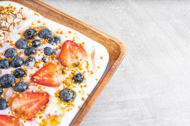 Closeup delicious and healthy breakfast of yogurt, strawberries and blueberries with honig pollen - Zdjęcie, obraz