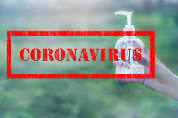 Coronavirus sign stamp and transparent white plastic bottle of antibacterial sanitizer fluid in hands with clear green background copy space - Fotografie, Obrázek