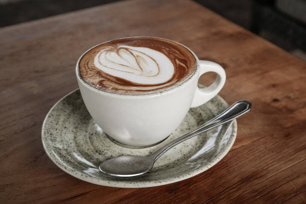 A cup of coffee with latte art on top on wooden table, top view - 写真・画像