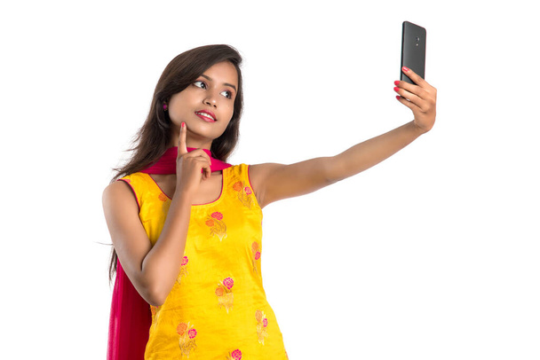 Young Indian girl using a Tablet, mobile phone or smartphone isolated on a white background - Foto, Imagen