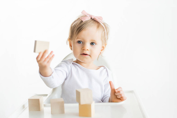 Little child shows wooden block. Children educatoinal by the Montessori method. Eco friendly wood toys. Toddler isolated on white background. - Fotografie, Obrázek