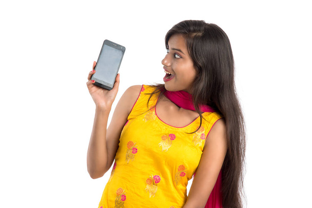 Young beautiful woman holding and showing blank screen smartphone or mobile or tablet phone on a white background. - Foto, Imagen