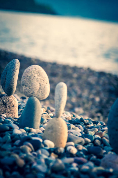 De zomer komt binnenkort in een pandemie. Een verlaten strand aan de Zwarte Zee. Beeldhouwwerken van stenen, een symbool van mensen. Stenen mensen. Imitatie van geliefden. Kunstinstallatie van kiezelstenen. Meditatie op zee. - Foto, afbeelding