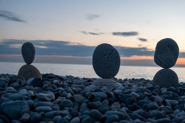 夏はすぐにパンデミックになりつつある。黒海の無人島の都市のビーチ。石の彫刻、人々のシンボルです。石の人だ。恋人の模倣。小石からのアートインスタレーション。海での瞑想. - 写真・画像