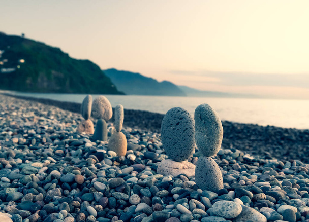 De zomer komt binnenkort in een pandemie. Een verlaten strand aan de Zwarte Zee. Beeldhouwwerken van stenen, een symbool van mensen. Stenen mensen. Imitatie van geliefden. Kunstinstallatie van kiezelstenen. Meditatie op zee. - Foto, afbeelding