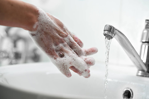 Жінка користується милом і миє руки під водопровідним краном. Очищення рук. Гігієна. Рожевий манікюр. М'який фокус
 - Фото, зображення