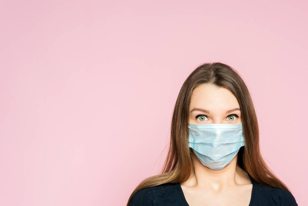 Jeune femme effrayée dans un masque de protection sur un fond rose. Peur et horreur de la pandémie de coronavirus
. - Photo, image