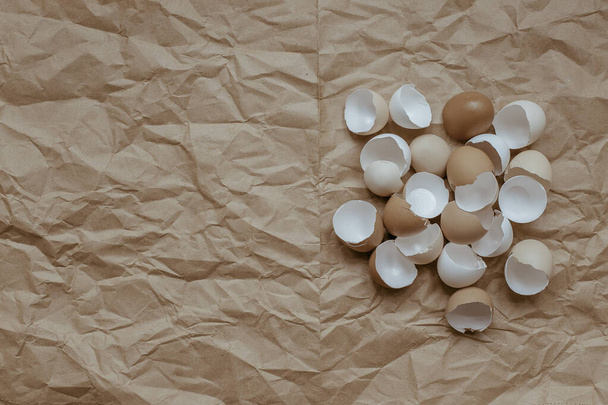 Textura de cáscara de huevo vacía rota sobre un fondo de papel kraft marrón arrugado. Vista desde arriba. Espacio de copia
. - Foto, Imagen