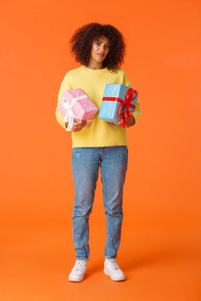 Full-length vertical shot gloomy and displeased picky african-american girlfriend displeased with amount of winter holidays presents, holding two boxed gifts and grimacing dissatisfied - Zdjęcie, obraz