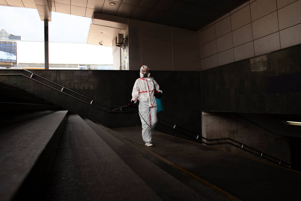 Coronavirus pandemie. desinfectiedienst werknemer in een beschermend pak reinigt de straten van de stad van virus en infectie met chemicaliën, stadsisolatie - Foto, afbeelding