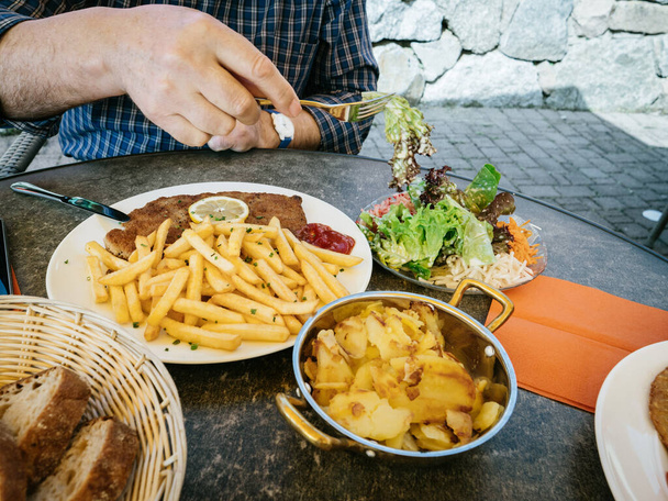 Osamělý senior - mužská ruka jí čerstvý bio bio bio salát z velkého pokrmu Německý řízek s pečenými hranolkami a hranolky brambory oblečené se salátem - Fotografie, Obrázek
