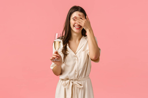 Happiness, celebration and party concept. Carefree romantic and delighted caucasian female in luxurious dress, laughing cover face as hearing hilarious joke, have fun, raising glass champagne - Photo, Image