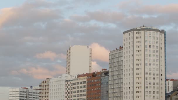 Roodachtige zonsondergang wolken boven gebouwen in A Corua - Video