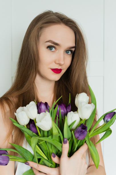 A beautiful girl is holding a big bouquet. A girl with a bouquet of tulips. - Valokuva, kuva