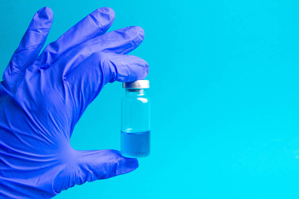 Üveg a Covid-19-es gyógymóddal. Orvos, nővér vagy tudós kéz a kék kesztyűben tart egy vakcina koronavírus. - Fotó, kép