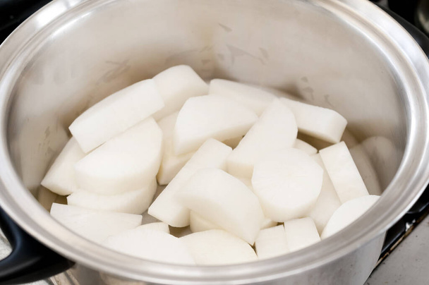 Trancher le radis japonais dans une casserole en acier inoxydable avant la cuisson
. - Photo, image