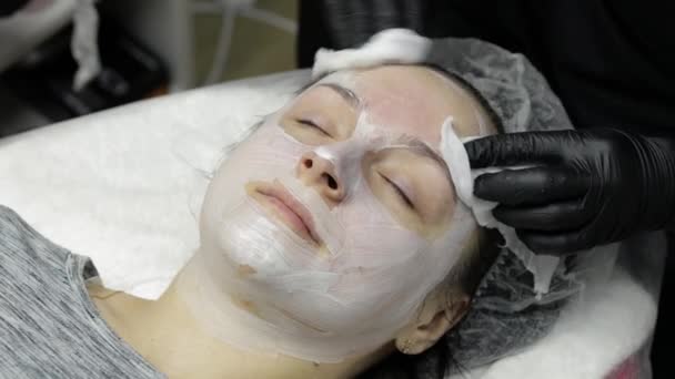 Cosmetologist καθαρό clien γυναίκα πρόσωπο από ενυδατική μάσκα στο σαλόνι ομορφιάς - Πλάνα, βίντεο