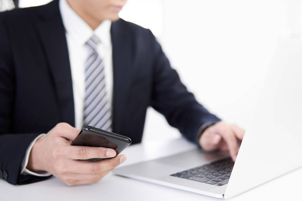 A Japanese male businessman enters data on his smart phone - Fotoğraf, Görsel