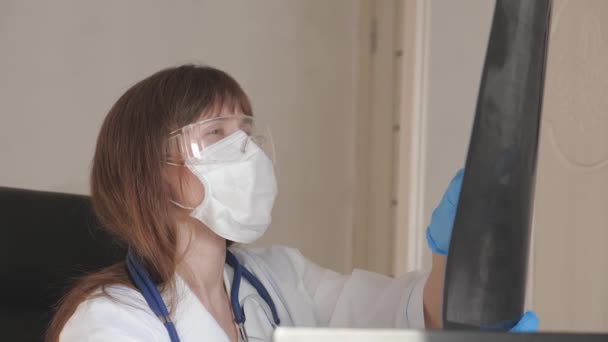 Female doctor pediatrician in office examines an x-ray of child of patient in a hospital. the doctor works in hospital. Medical care and healthcare concept. coronovirus pandemic, pneumonia - Video