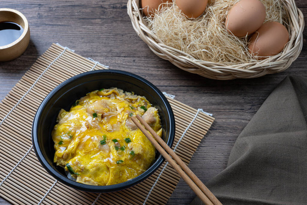 Oyako-don rice bowl topped with chicken, onions and egg cooked with special sauce. oyakodonburi Japanese food on wooden background. - Photo, Image