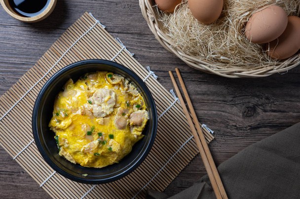 Oyako-donová rýžová mísa s kuřecím masem, cibulí a vejcem vařeným se speciální omáčkou. oyakodonburi japonské jídlo na dřevěném pozadí. pohled shora. Plocha. - Fotografie, Obrázek