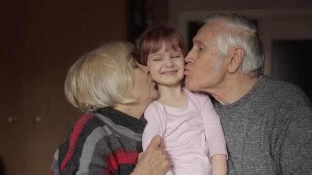 Abuelo y abuela besando en las mejillas a su nieta en casa
 - Imágenes, Vídeo