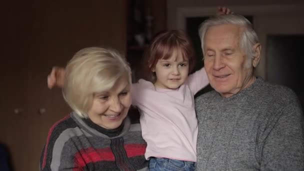 Vnučka objímá staršího usměvavého dědečka s babičkou doma - Záběry, video