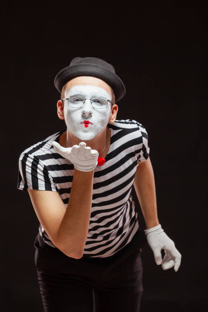 Portrait of male mime artist performing, isolated on black background. Man leaned over to blow a kiss - Fotoğraf, Görsel