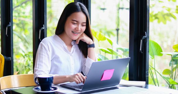 美しいアジアのビジネス女性は、文書をチェックし、社会的距離と自己責任の概念のために自宅から働くノートブックを使用して - 写真・画像