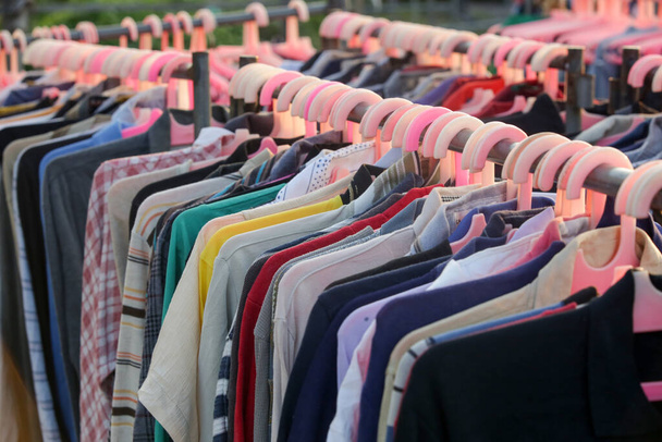 Enorme selectie van verschillende tweedehands kleding voor mannen, vrouwen en kinderen op het rek in een tweedehands winkel of kringloopwinkel. Begrip afvalprobleem in de mode-industrie. - Foto, afbeelding