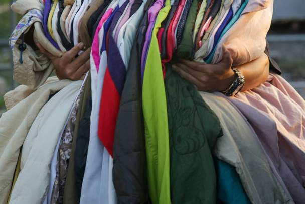 Enorme selectie van verschillende tweedehands kleding voor mannen, vrouwen en kinderen op het rek in een tweedehands winkel of kringloopwinkel. Begrip afvalprobleem in de mode-industrie. - Foto, afbeelding