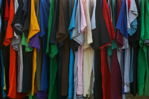 Hatalmas a választék a különböző használt ruhák a férfiak, nők és gyermekek számára az állványon egy használt bolt vagy takarékos bolt. A hulladékprobléma fogalma a divatiparban. - Fotó, kép