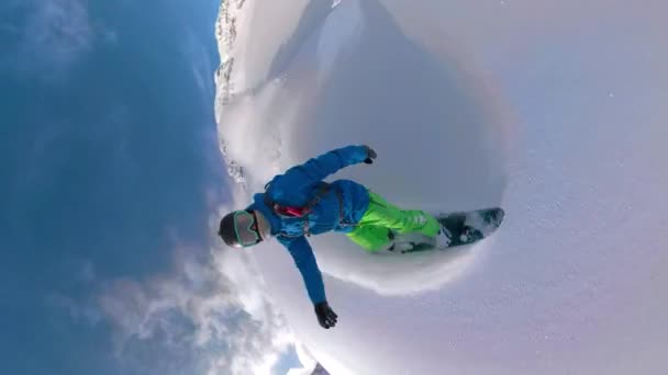 VERTICAL: Snowboarder desmenuza el polvo fresco y rocía la nieve en la cámara
. - Metraje, vídeo
