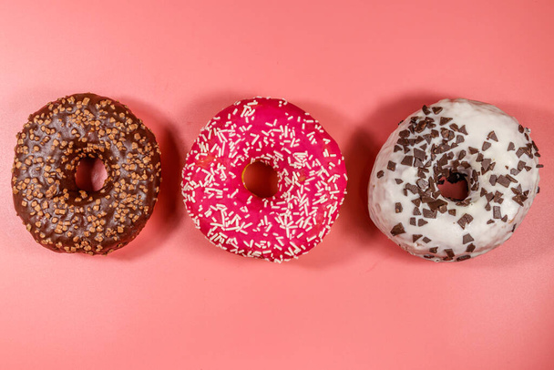 Lekkere donuts op roze achtergrond. Bovenaanzicht - Foto, afbeelding