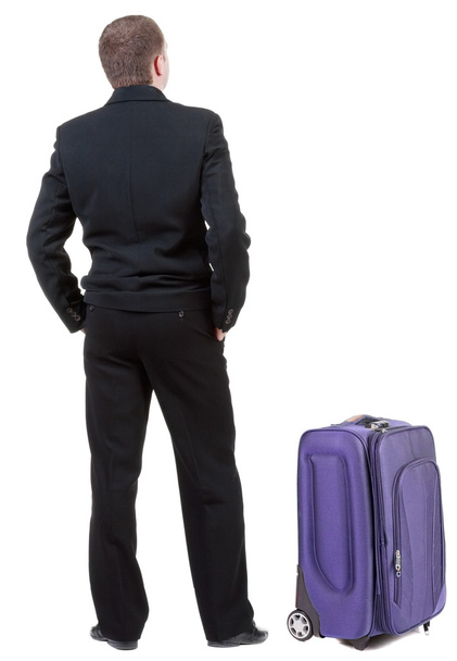 Back view of adult man in black suit traveling with suitcase. - Fotó, kép