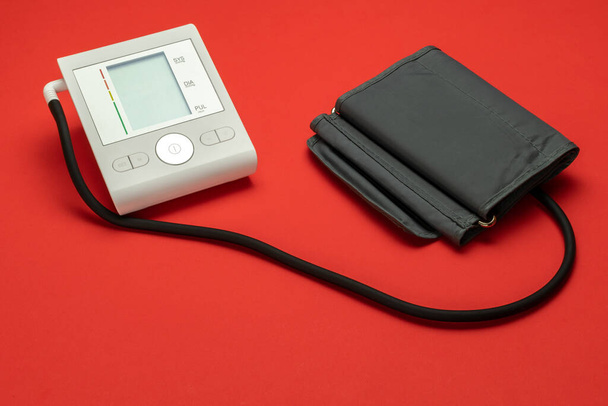 Bloeddrukmeter. Medische test monitor voor bloeddruk geïsoleerd op rode achtergrond. Harthypertensiecontrole met sfygmomanometer voor arts, patiënt. Technologie voor ziekenhuisdiagnostiek - Foto, afbeelding