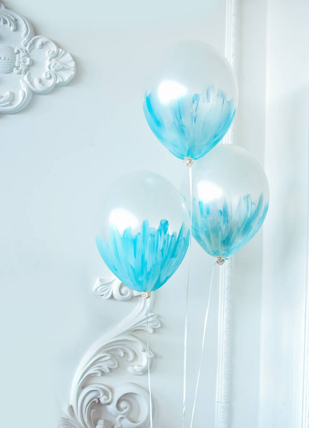 Three blue balloons on a light background indoors. Holiday atmosphere - Fotó, kép