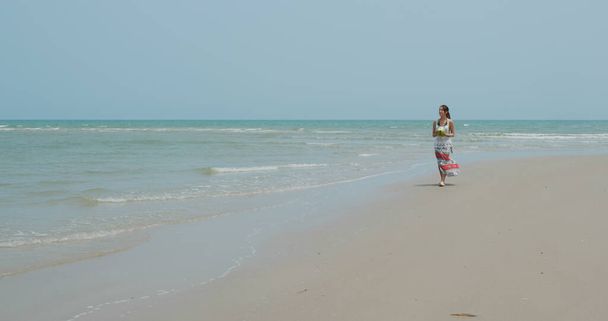 Frau trinkt Kokosnuss und spaziert am Strand - Foto, Bild