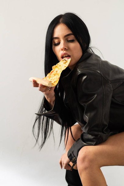 Restaurant food. Attractive woman leather jacket naked body eating pizza. Tempting dish. Seductive meal. Fast food. Diet and healthy body. Sexual appetite. Sexy girl eating pizza. Pizza delivery - 写真・画像