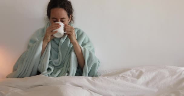 Caucasian woman spending time at home self isolating and social distancing in quarantine lockdown during coronavirus covid 19 epidemic, coughing, holding a mug and drinking - Imágenes, Vídeo