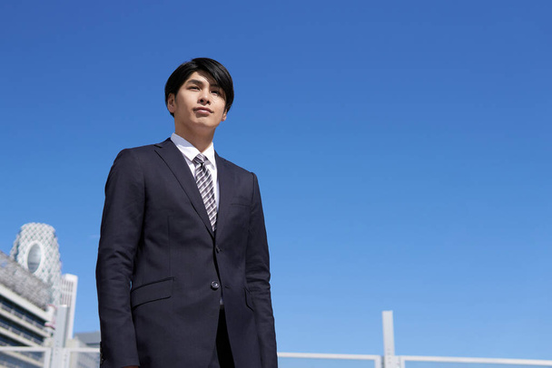 A Japanese male businessman stands in an office district. - Photo, Image