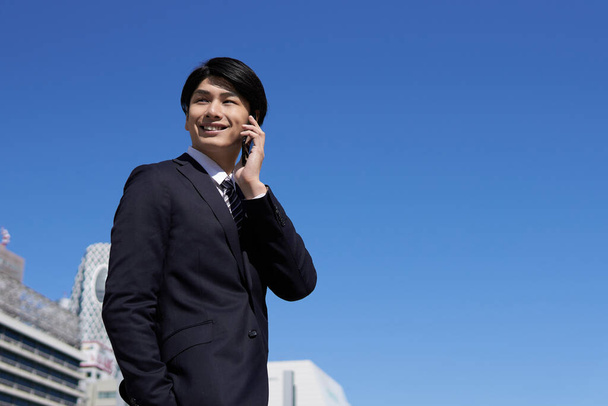 Japanilaiset miespuoliset liikemiehet tekevät puheluja älypuhelimillaan
. - Valokuva, kuva