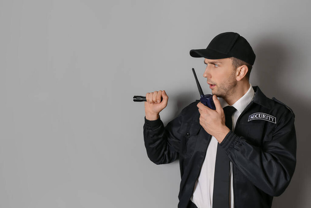 Mannelijke bewaker met zaklamp op grijze achtergrond - Foto, afbeelding