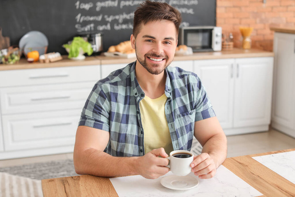Young man drinking hot coffee in kitchen - Foto, Imagem