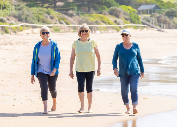 Gruppe von drei Senioren Rentnerin aus Altenheim zu Fuß zusammen am Strand. Trainieren Sie im Freien Hoffnung und zurück ins Leben nach Coronavirus Lockdown-Konzept. - Foto, Bild
