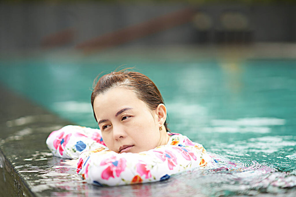 Ασιάτισσα αναπαύεται δίπλα στην πισίνα στην έννοια των διακοπών πορτρέτο - Φωτογραφία, εικόνα